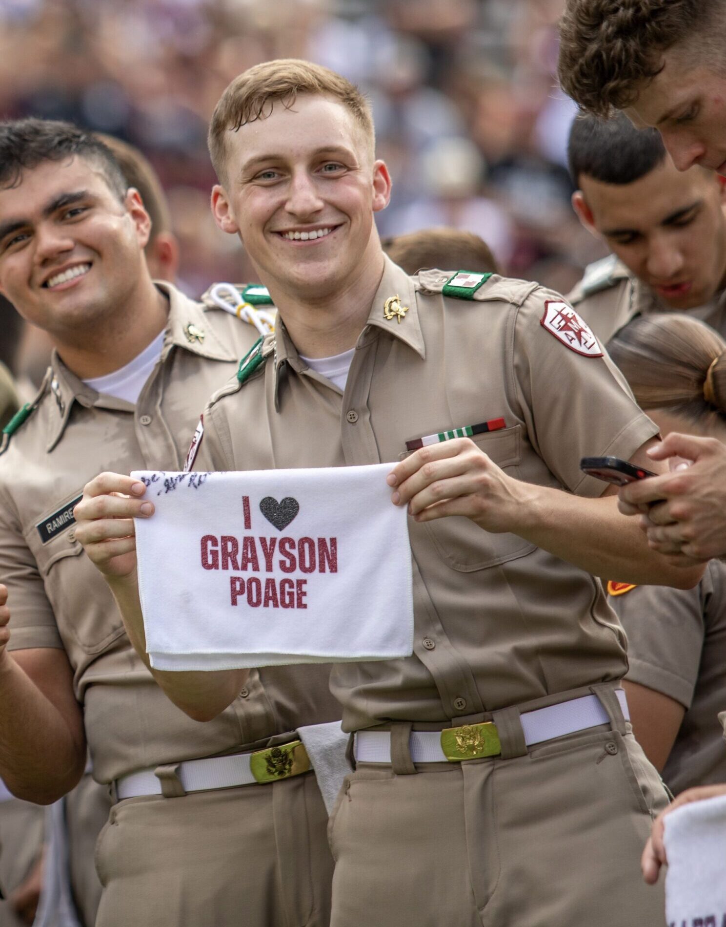Cadet Lucas Scroggins holds a 12th Man towel that reads ""I love Grayson Poage"