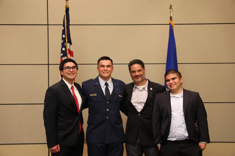 Four men standing in suites between flags.