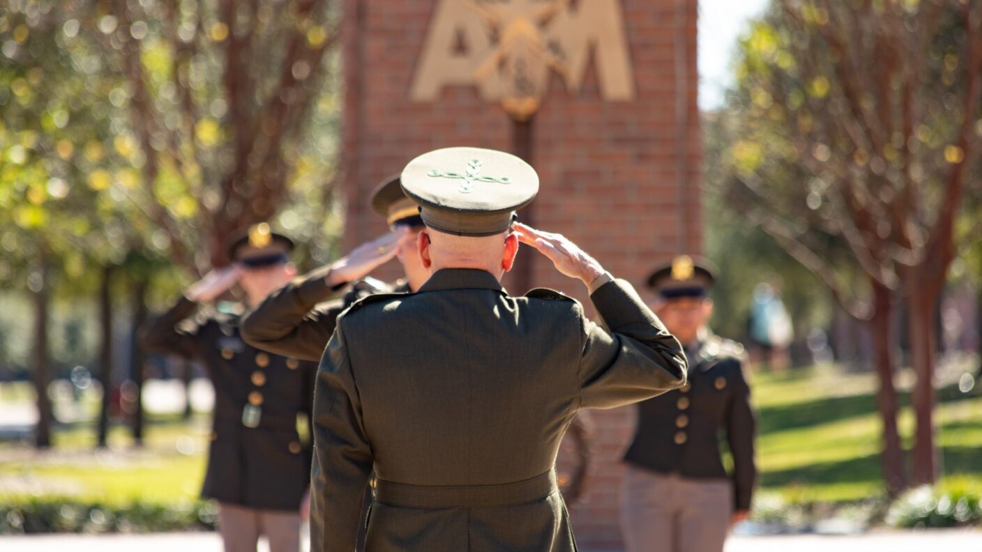 The back of a Colonel saluting cadets in the background.