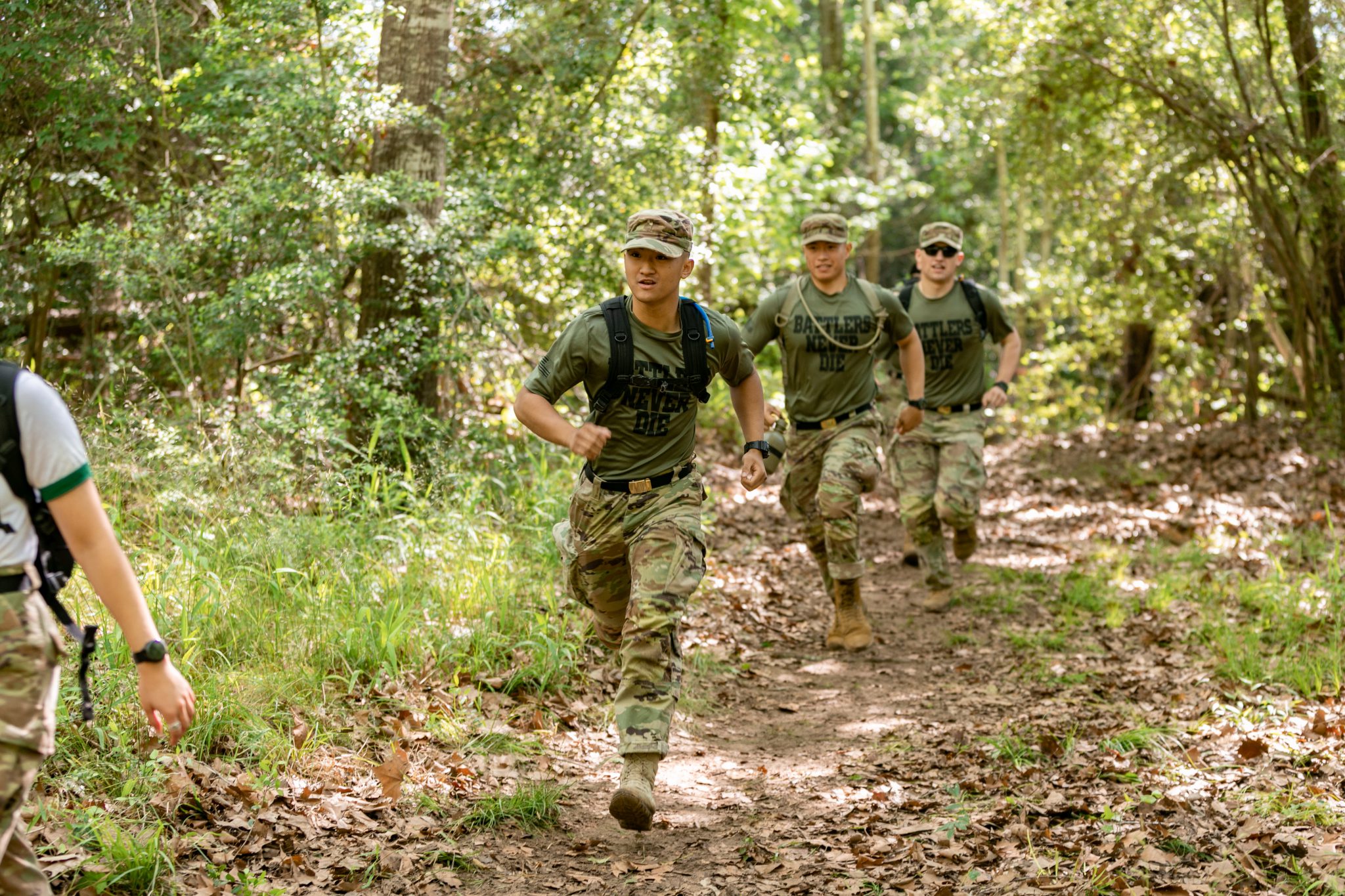 Three men running in a forest.