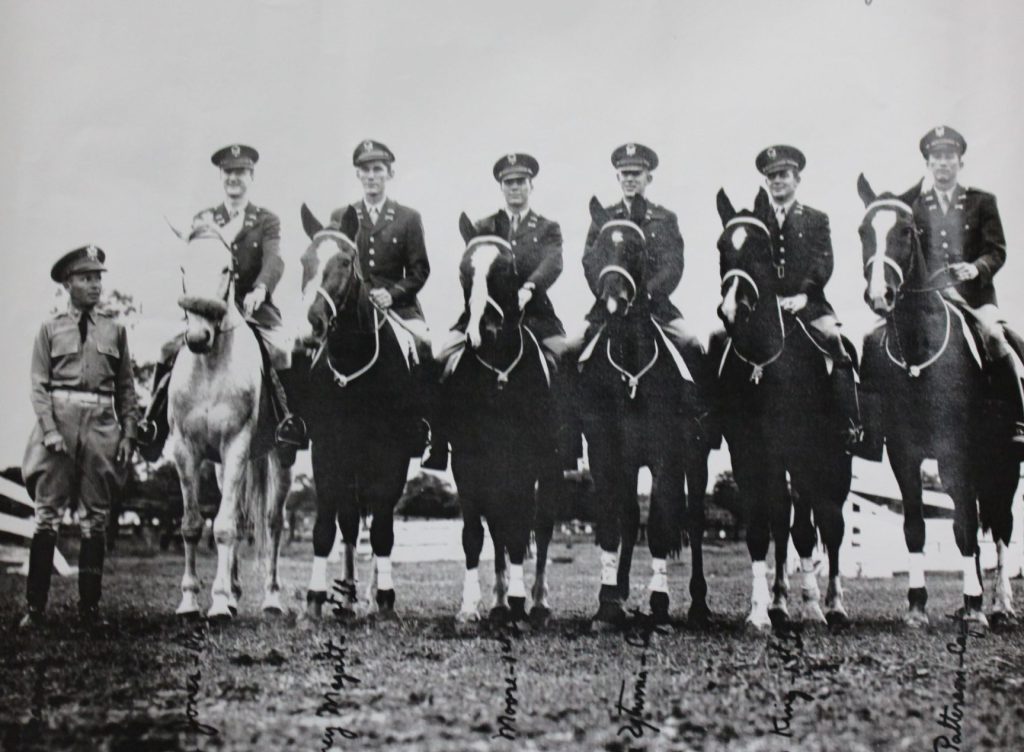 Black and white photo of people on horses.