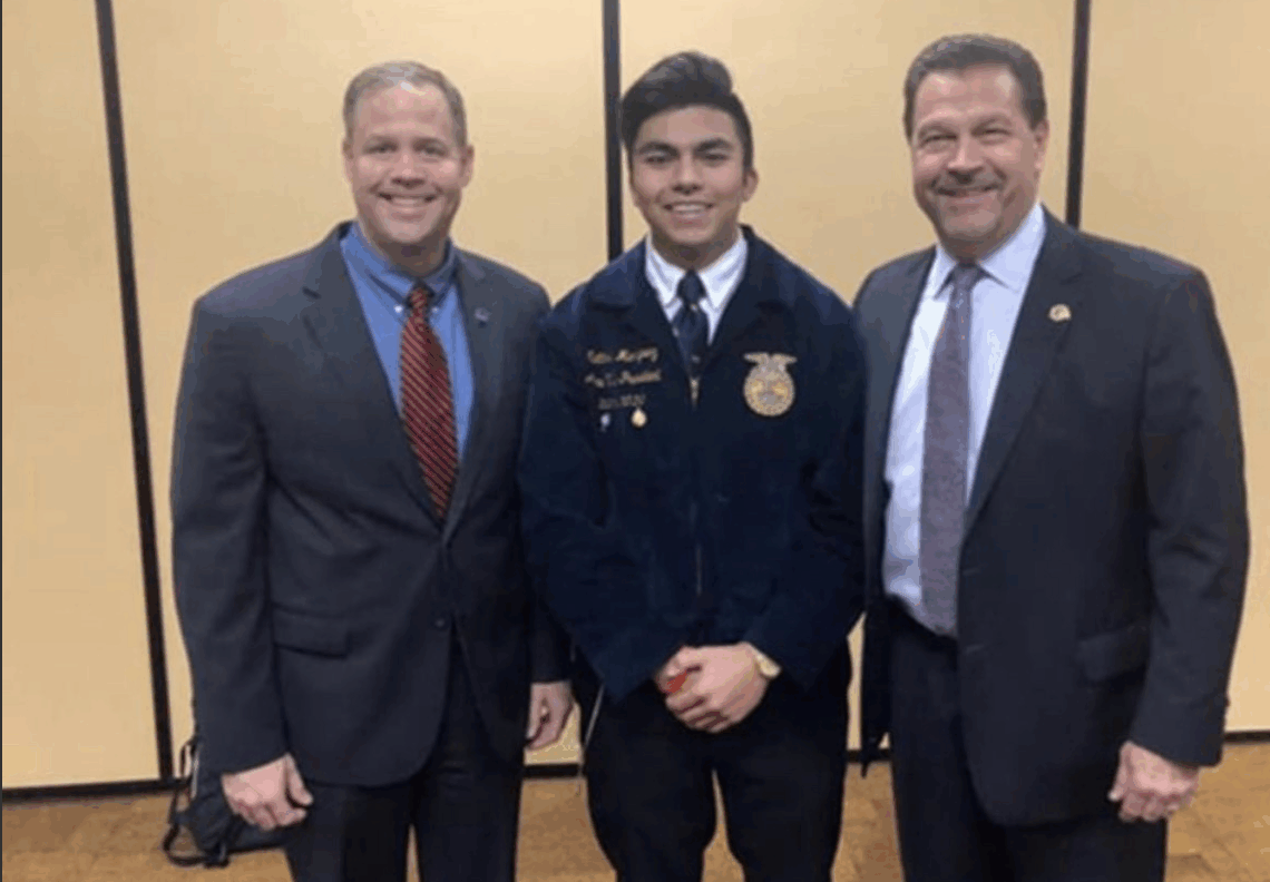 Three men standing together dressed nicely.