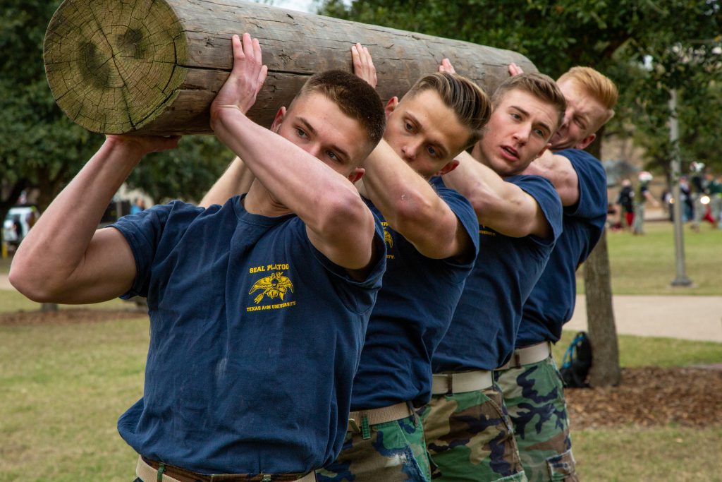 Four men carrying a log on their shoulders.