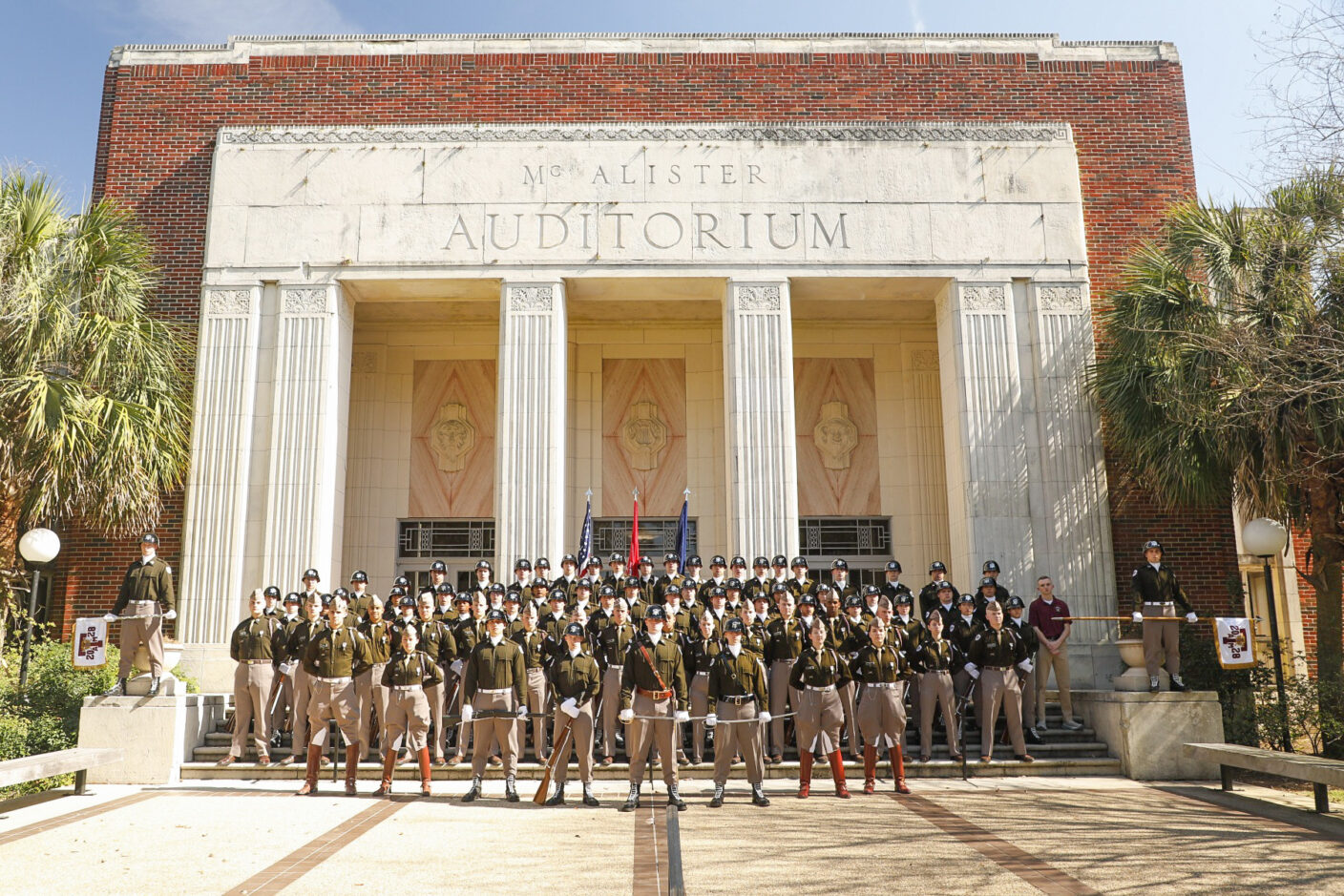 A group of cadets standing in front of a building.