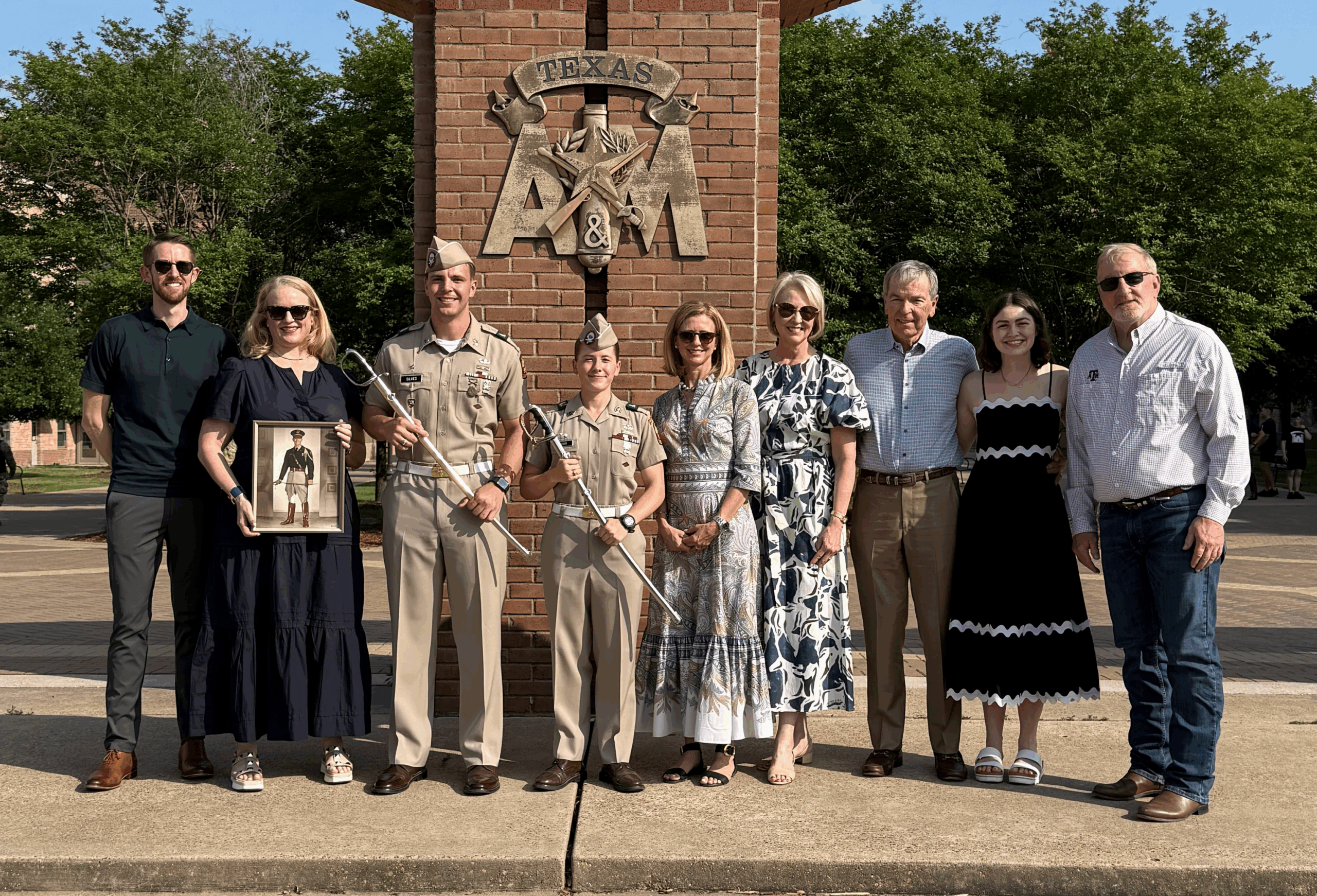 A family poses in front of the arches holding photo frames and sabers.