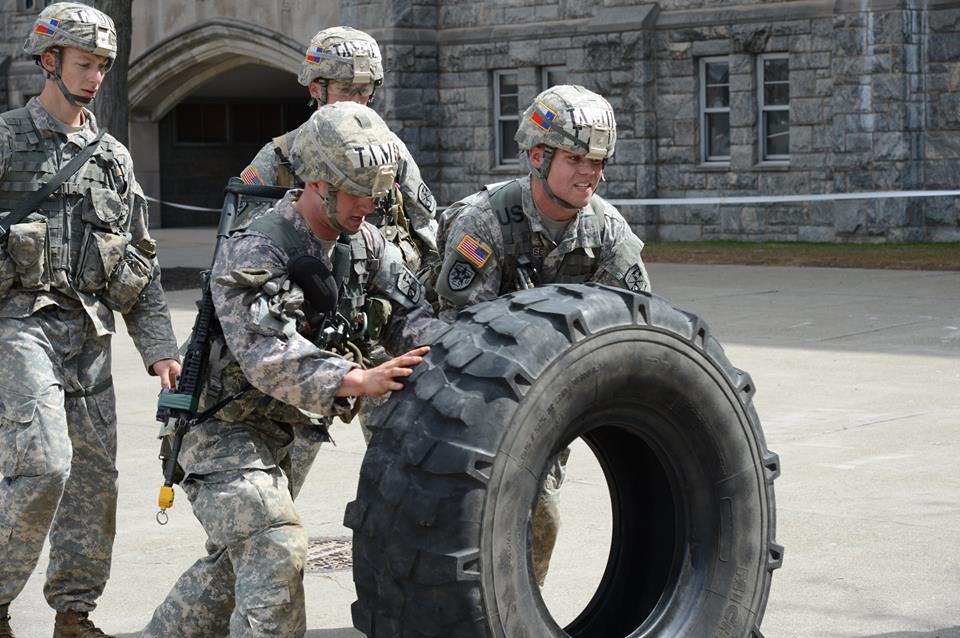 Two guys working together to flip a tire.