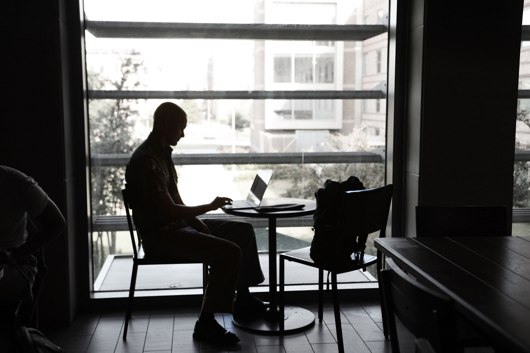A cadet sitting at a table with his notes and backpack out.