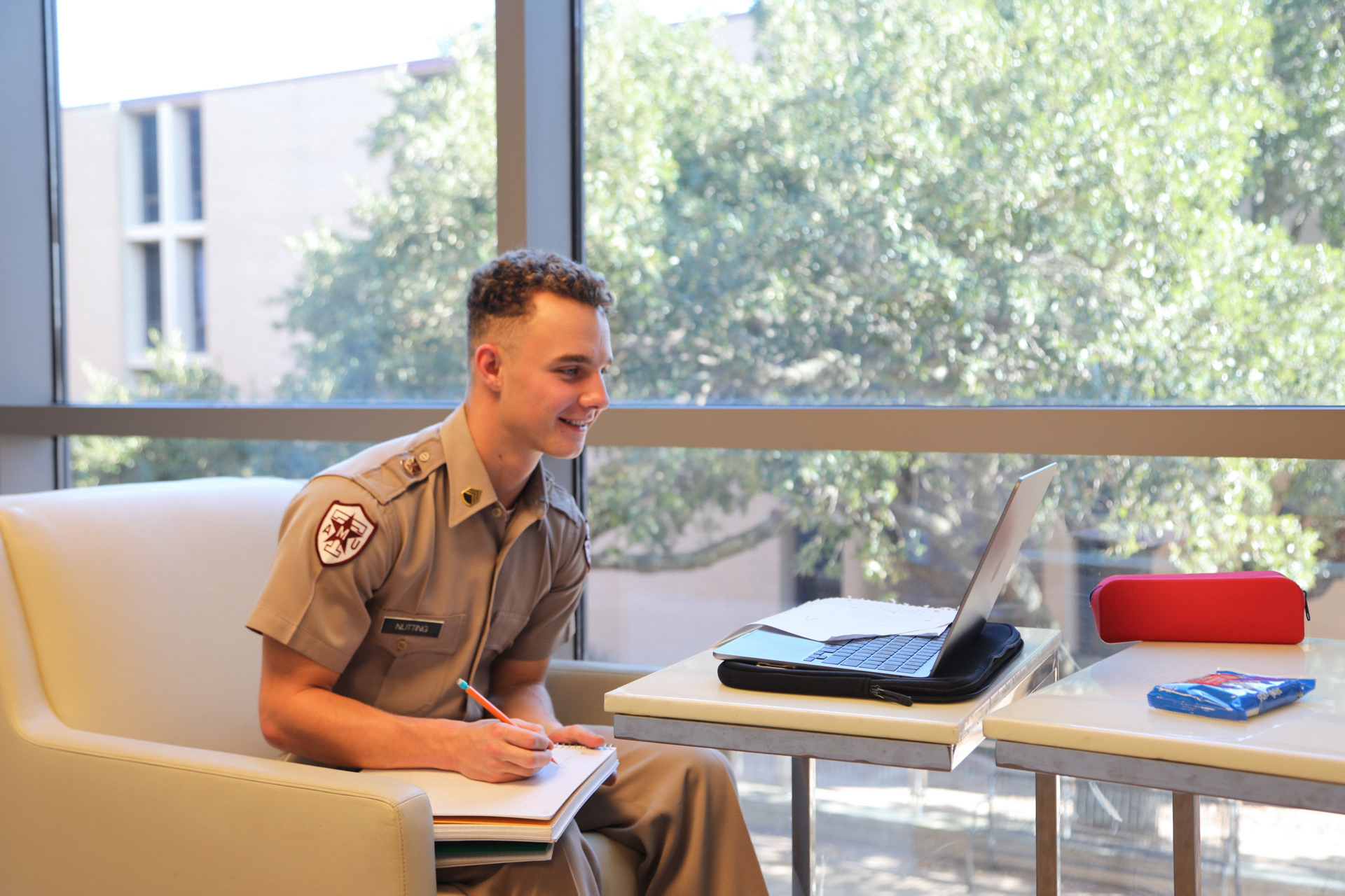 A cadet in uniform studying at a table.